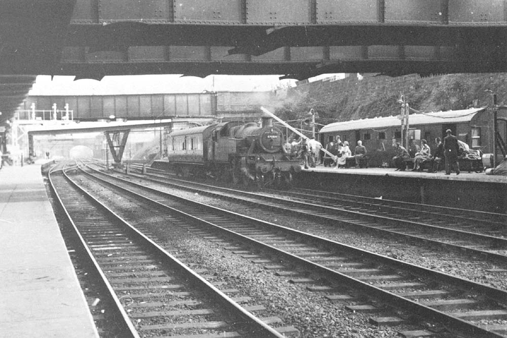 View of ex-LMS Ivatt 2-6-2T No 40104 at the head of a single parcels van used to transport luggage and parcels from the down platform  to the up platform