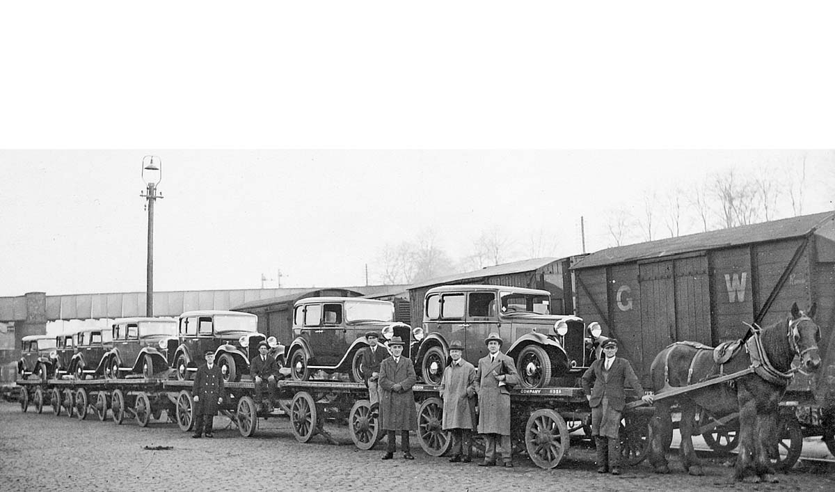 View of seven Hillman cars being transported to Coventry Goods yard by horse drawn trailers