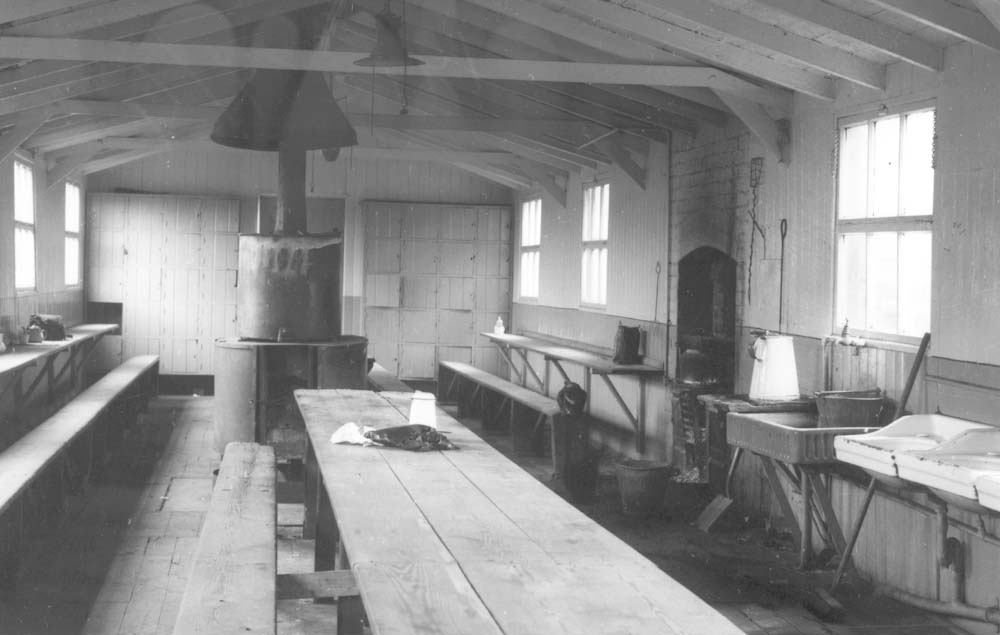 View of the inside of the mess hut showing the range of equipment including fireplace, boiler and washbasins