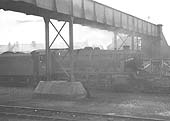 An unknown ex-LMS 8F 2-8-0 locomotive stands beneath the footbridge crossing Gosford Green goods yard