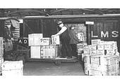 A view of a gang in the process of transferring merchandise from a LMS electrical trolley to a van