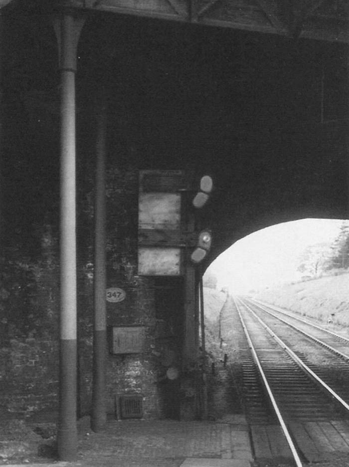 View of the down platform starter signal located at the end of the Birmingham end of the down platform beneath the road bridge on 23rd May 1955