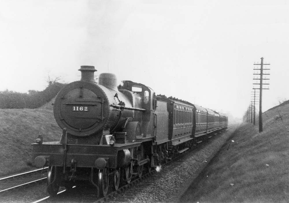 LMS 4-4-0 Compound No 1162 is seen at the head of a down express approaching Hampton in Arden station