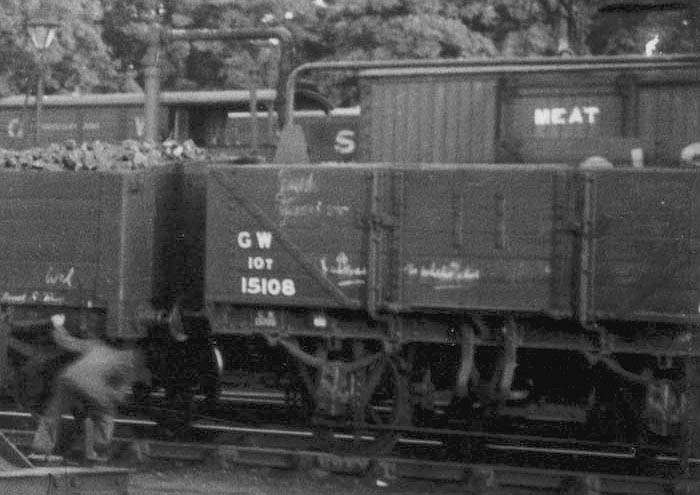 Close up of a railway workman inspecting the brake gear on the mineral wagons standing in the exchange sidings with the GWR