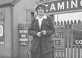 A lady L&NWR ticket collector poses for the camera in front of Leamington station's nameboard
