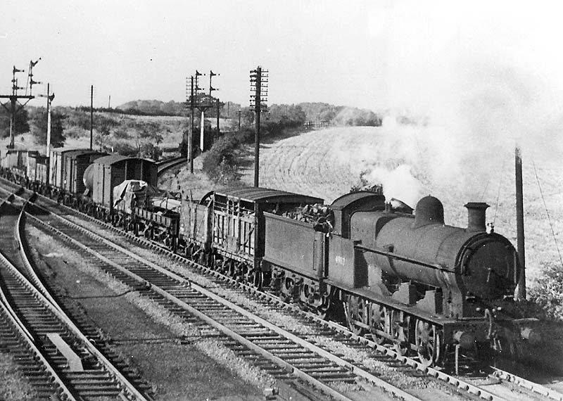 Ex-LNWR 0-8-0 class G2a No 49117 is seen at the head of a goods train on the slow up line as it passes the junction of the branch to Ashby