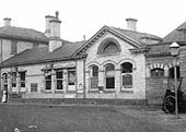 Close up showing Nuneaton station's refreshment and general waiting rooms and one of the station staff posed by delivery entrance
