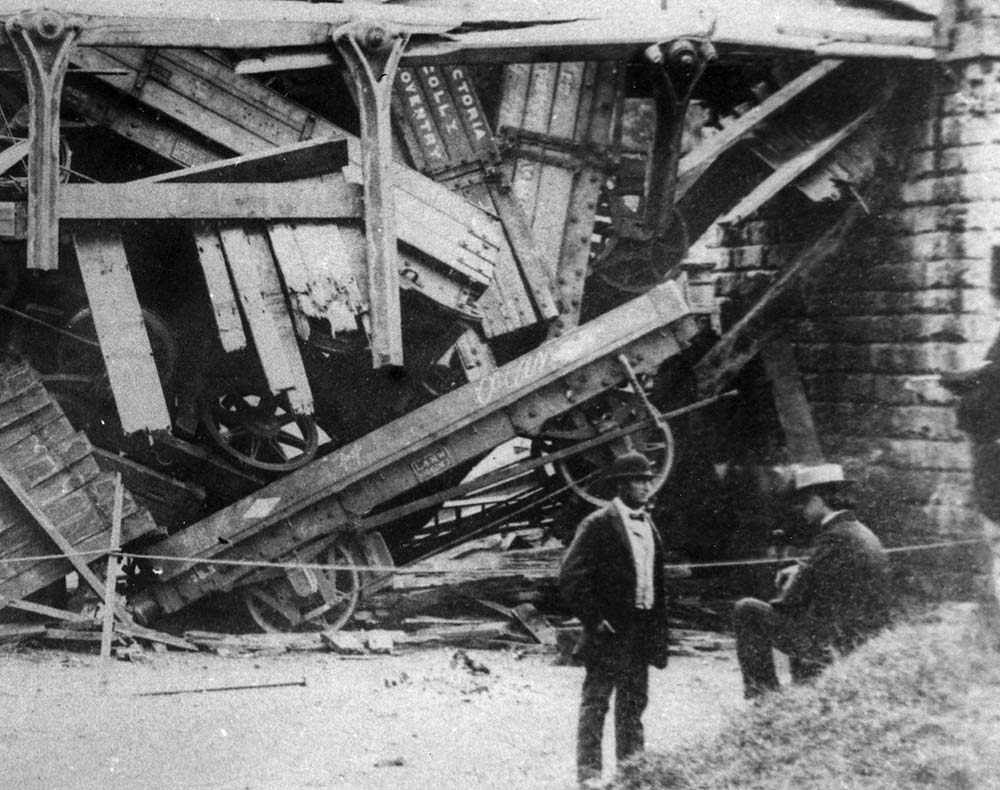 Close up showing a single-plank flat wagon with the L&NWR diamond marking lying beneath the wreckage