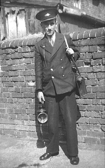 'Bill 'Jock' Bailey stands with lamp in hand in his guard's uniform at the rear of No 7 New Station cottage