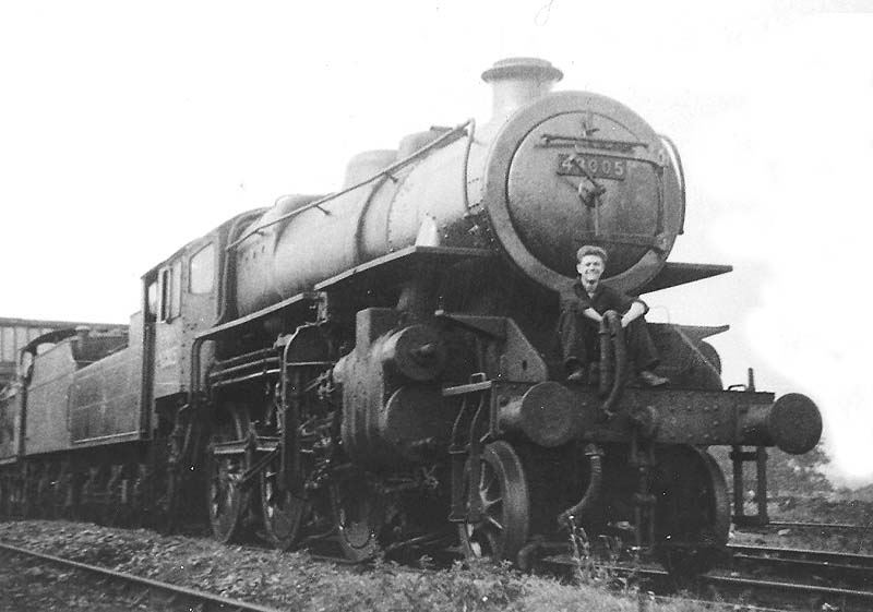 British Railways built 4MT 2-6-0 No 43005 stands outside of Rugby No 2 shed with an unknown fireman sitting on the front buffers