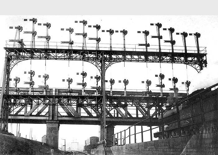 Ex-LNWR 4-6-0 Prince of Wales class No 25673 'Lusitania' waits for a clear road under Rugby Signal Gantry