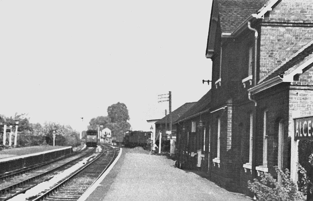 View along the down platform towards Redditch as a freight train is seen shunting in the yard