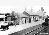 Edwardian view of the station showing a young porter ready to load luggage on to the incoming train