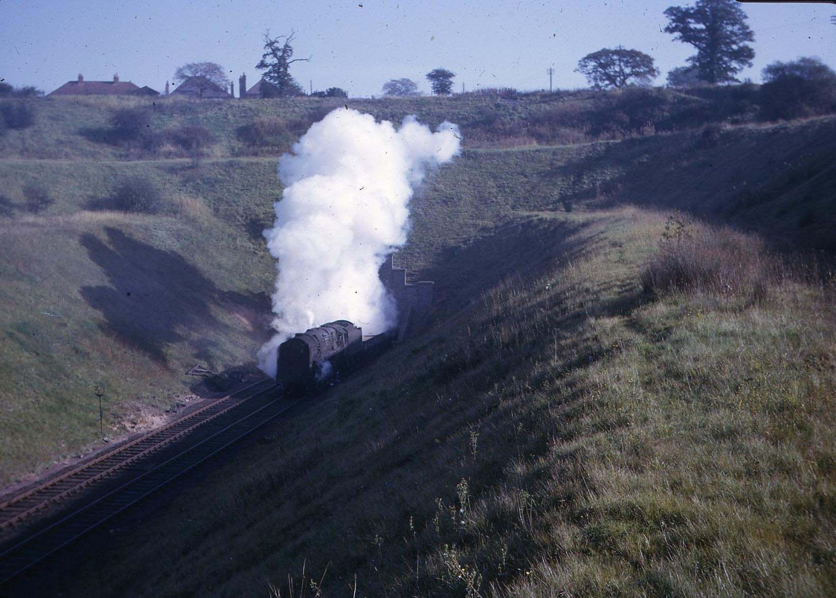 An unidentified British Railways 2-10-0 9F locomotive emerges from the tunnel at the head of a freight train on 16th October 1965