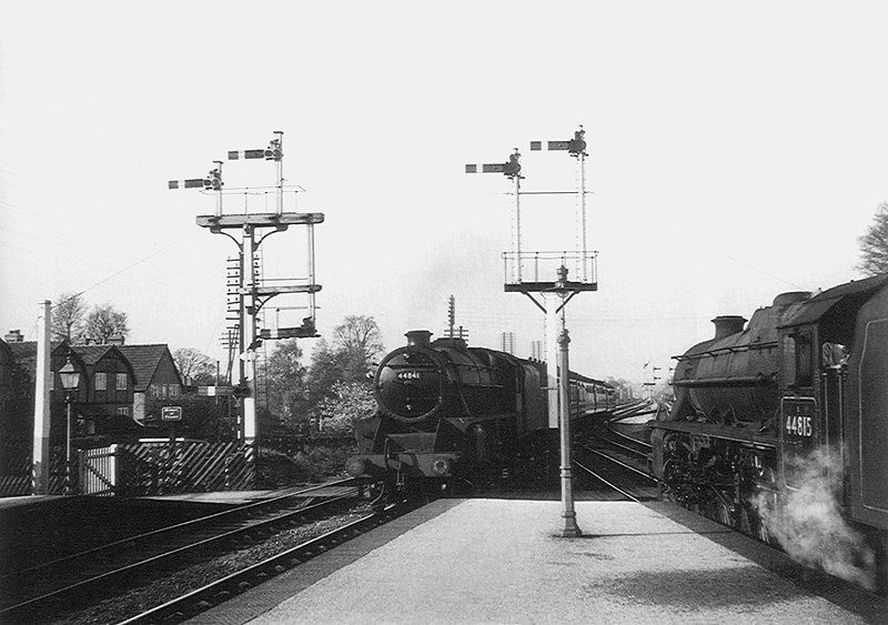 Ex-LMS 4-6-0 Black 5 No 44841 enters Barnt Green station on a down express as classmate No 44815 waits at the signals