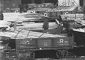 Close up showing the timber planking being transferred to horse-drawn road vehicles for onward distribution