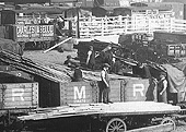 Close up showing a typical gang of yard labourers at work off-loading timber from the open wagons