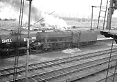 Ex-LMS 8F 2-8-0 No 48183 is running tender first through Bromford Bridge station with a mixed train including oil wagons
