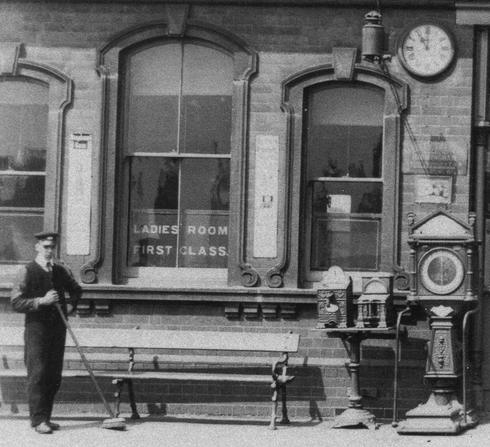 Close up showing two cast-iron mechanical vending machines and a luggage weighing machine