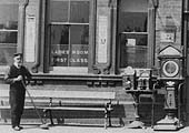 Close up showing two cast-iron mechanical vending machines and a luggage weighing machine