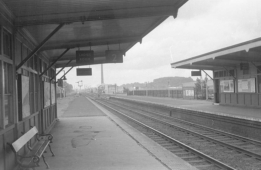 Looking along the station's up platform which has very little furniture evident other than the bench seat on the left