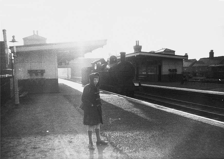 An unidentified ex-MR 3F 0-6-0 locomotive runs tender first and light engine through Castle Bromwich station's down platform in 1957
