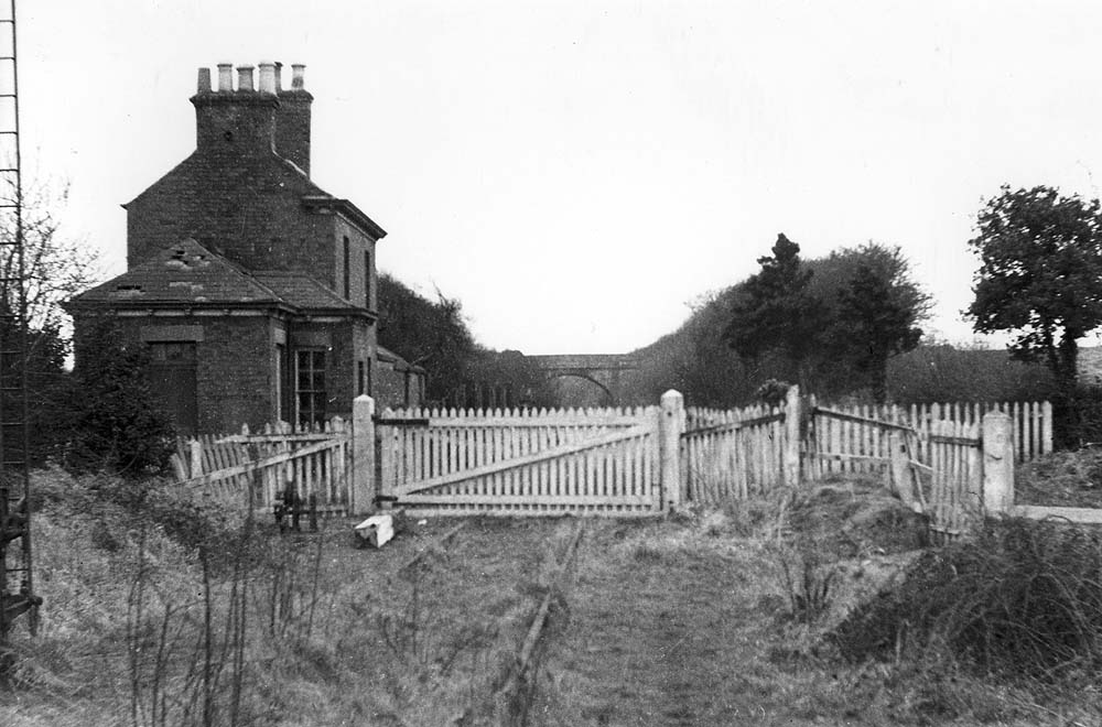 View of the station now abandoned with the level crossing in the foreground with the down signal still evident