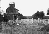 View of the station now abandoned with the level crossing in the foreground with the down signal still evident