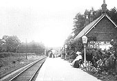 View of Coughton railway station looking towards Alcester with passengers and milk churns standing on the platform