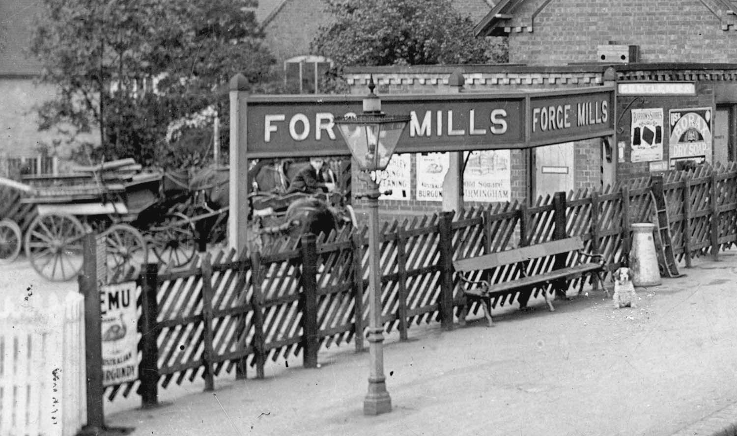 Close up of the distinctive MR Forge Mills station name board and the equally distinctive MR fencing with angled timbers