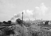 An unidentified ex-LMS 2-8-0 8F locomotive is seen coupled to a brakevan as it ascends the bank past Kingsbury Colliery