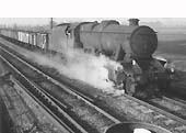 An unidentified ex-LMS 8F 2-8-0 locomotive rattles past Kingsbury Station Junction Signal Box circa 1966