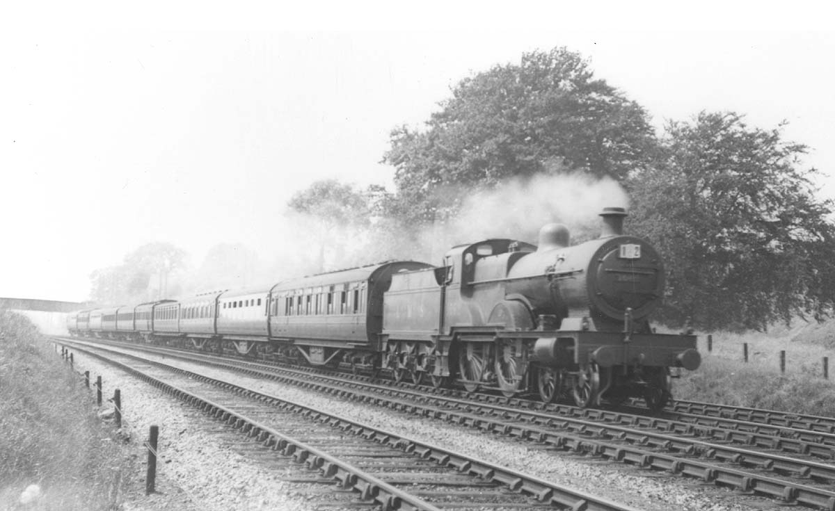 LMS 4-4-0 'Compound' 4P No 1062 storms past whilst at the head of a ten coach holiday express  passenger service during the summer of 1936