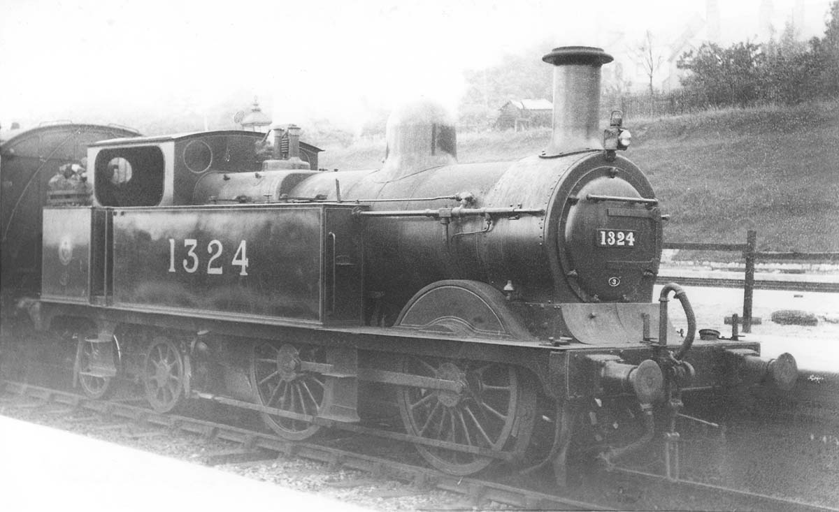 Ex-MR 1P 0-4-4T No 1324 wearing shed plate No 3 stands at the head of a local					passenger train in the station