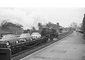 British Railways Standard Class 4MT 4-6-0 No 75043 runs tender first through Kings Norton station with a train of Morris Oxford or Austin Cambridge cars