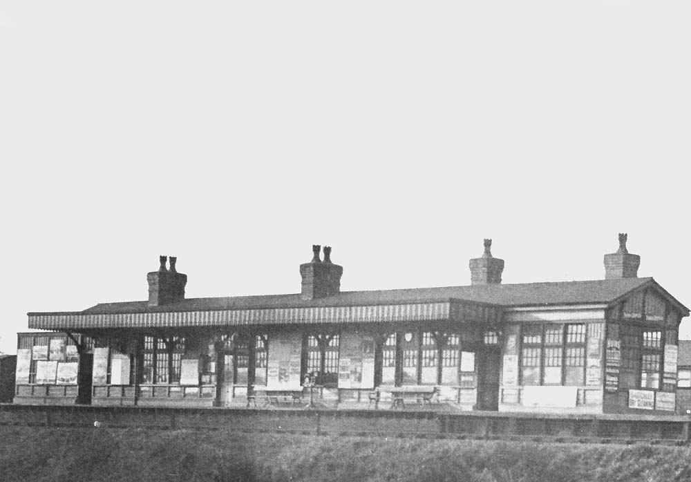 Close up showing Northfield Station's island platform building which is heavily covered in advertising posters