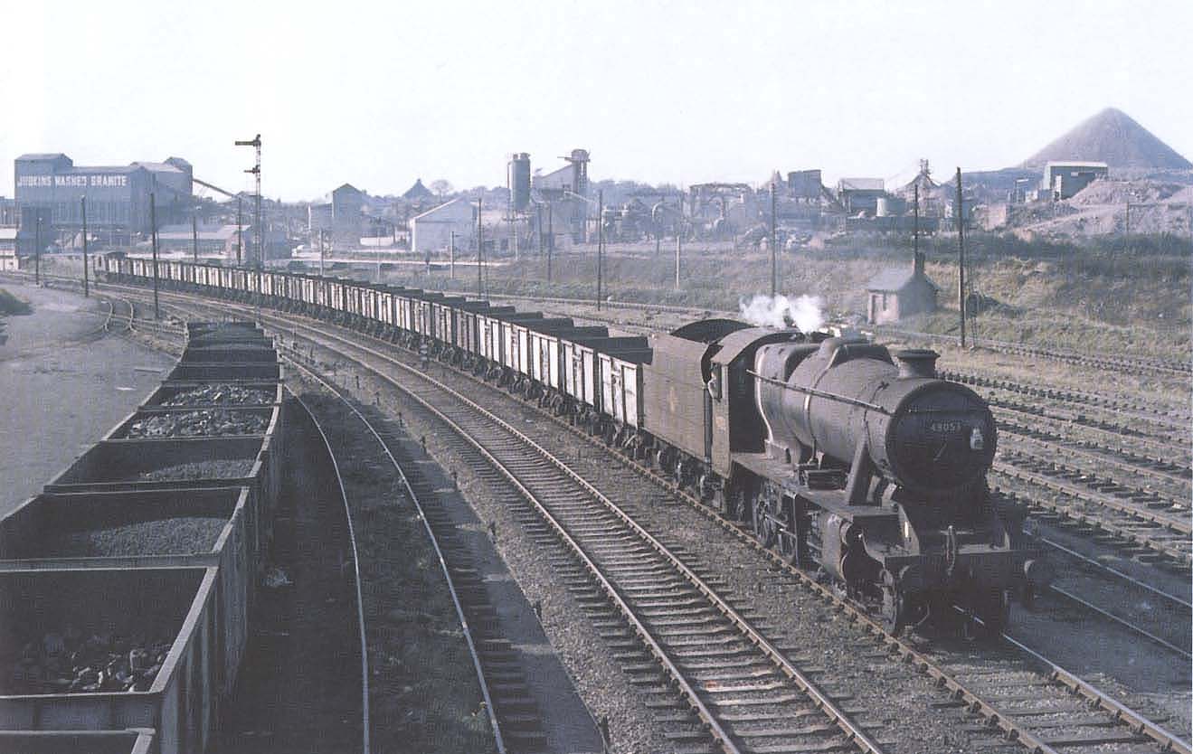 Ex-LMS 8F 2-8-0 No 48053 heads a long rake of steel bodied mineral wagons on a Leicester bound service on 3rd October 1964