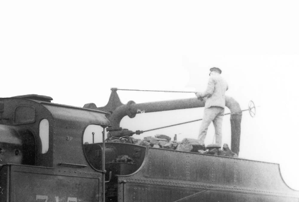 Close up of No 715's fireman topping up the locomotive's tender after trimming the coal as part of preparing the locomotive to go off shed