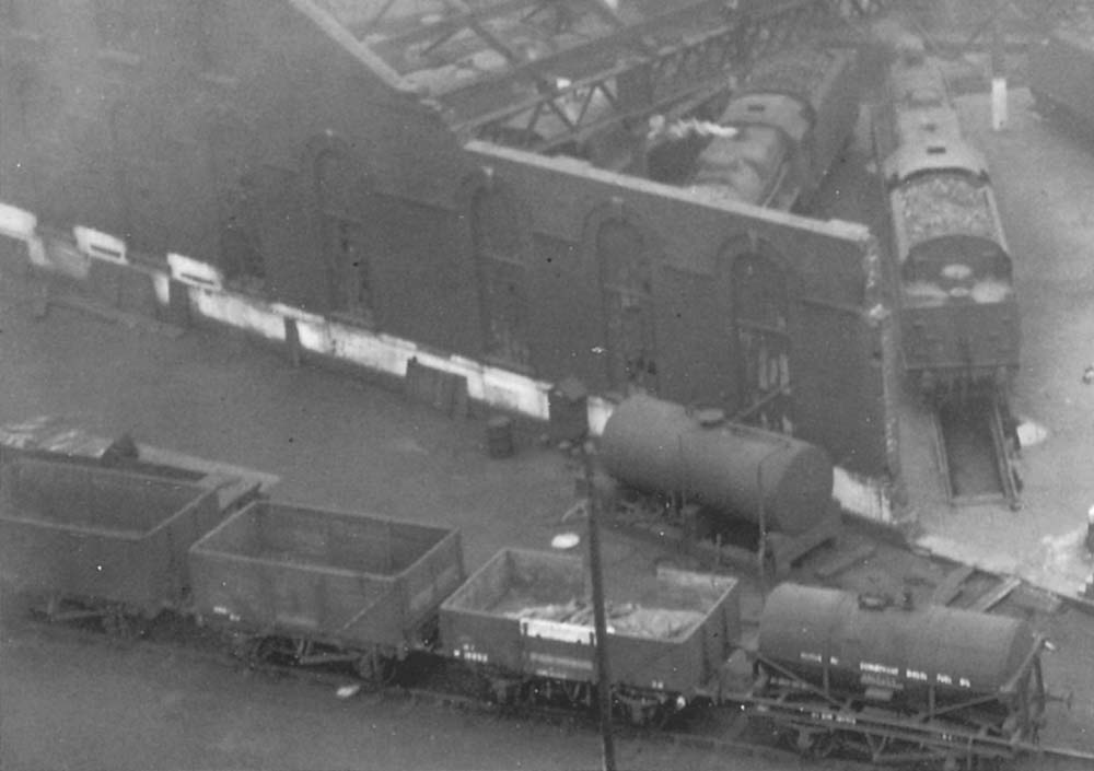 Close up of the corner of Saltley shed's war-damaged No 3 roundhouse and the open and tank wagons stored on the siding adjacent to an oil tank
