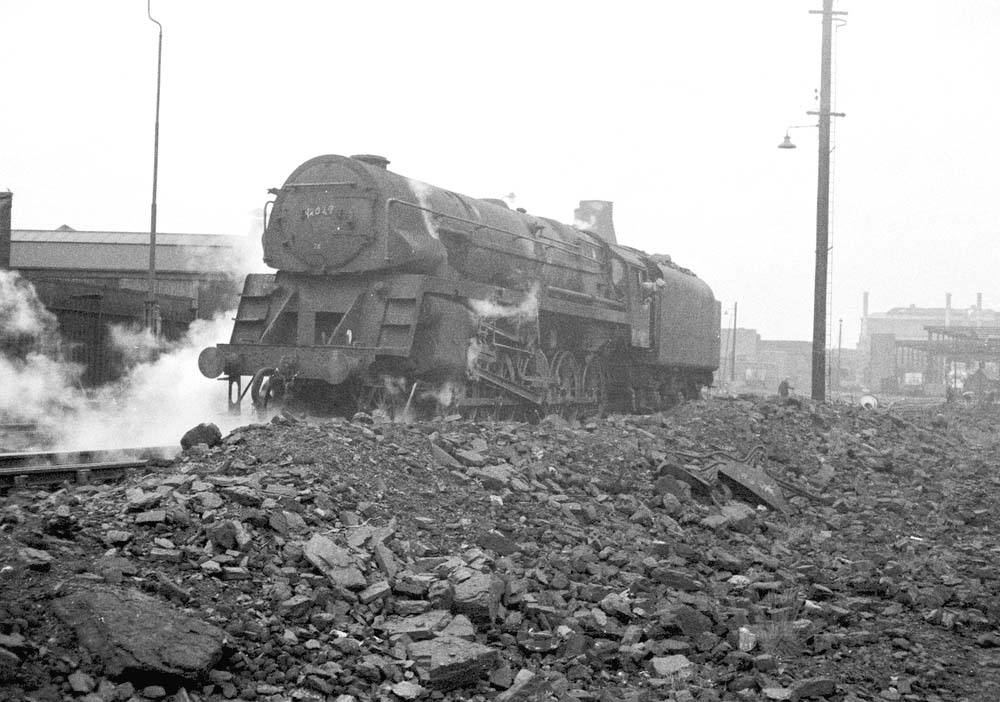 British Railways Standard Class Crosti-boilered 9F 2-10-0 No 92029 runs forward to clear the points outside the shed