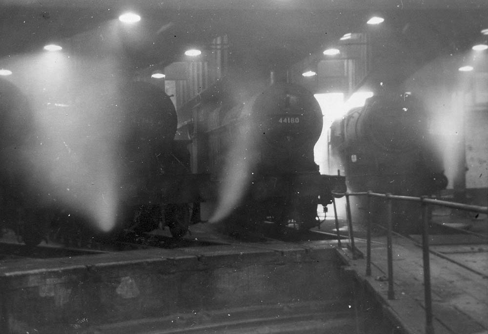 Ex-LMS 4F 0-6-0 No 44180 stands inside Saltley No 2 Shed as an unidentified BR Standard 4-6-0 enters the shed