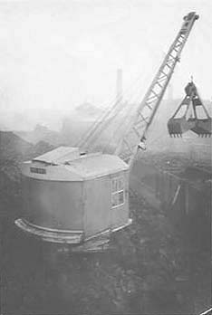 A crawler crane is seen loading coal from Saltley shed's coal stack into 'Loco' wagons to be taken to the Coaling Tower