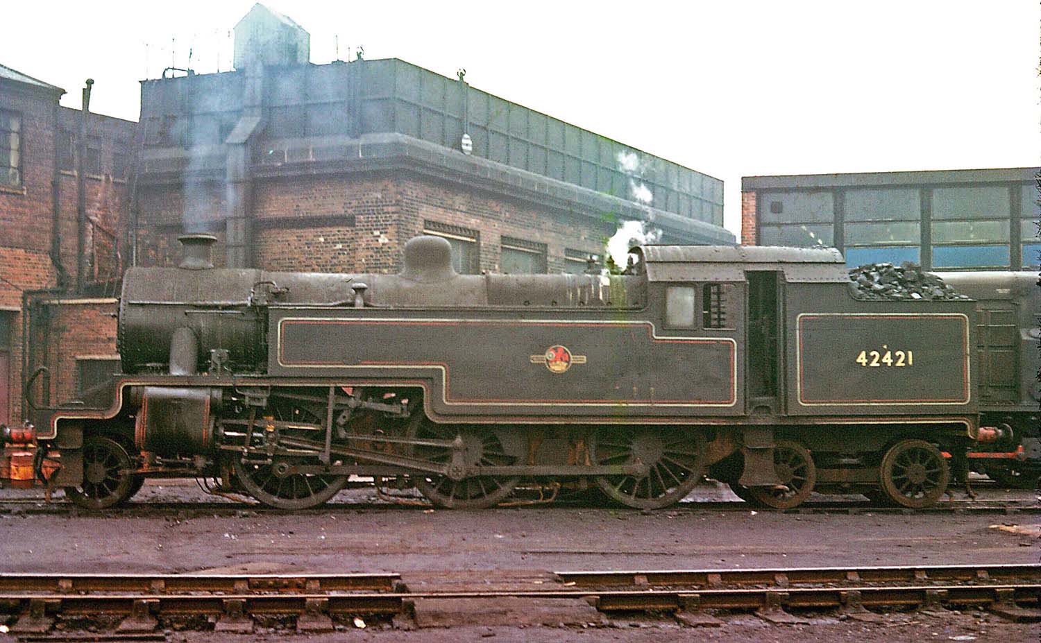 A broadside view of ex LMS 2-6-4T No 42421, standing in front of the offices, with water tank above, at Saltley shed