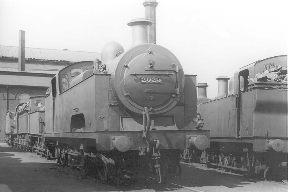 Ex-MR 0-6-4T 'Flatiron' No 2025 is standing alongside an unidentified 0-6-0T 'Jinty' on one of the stabling roads outside Saltley's No 3 roundhouse