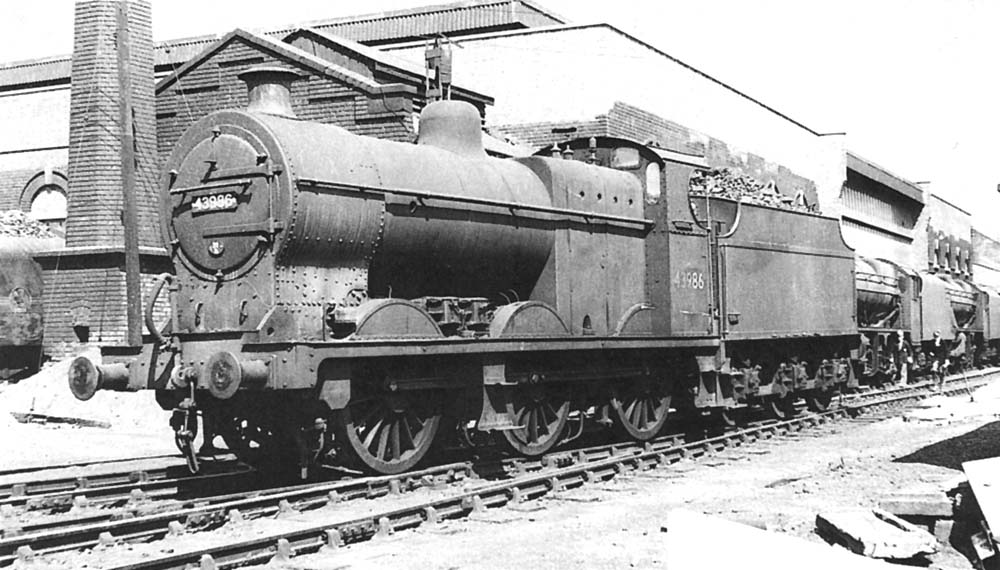 Ex-LMS 4F 0-6-0 No 43986 passes a number of 8F locomotives as it moves off shed in the late 1950s