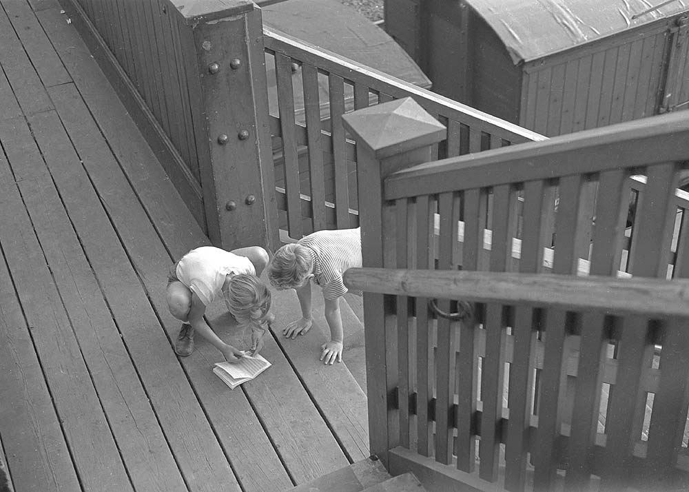 Two very young trainspotters position themselves halfway up the steps to catch the next train passing on either the London or Derby lines circa 1960