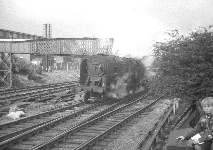 British Railways Standard Class 9F 2-10-0 No 92139 passes beneath the footbridge at Water Orton with a Class F express freight heading for Nuneaton