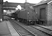 An ex-LMS 'Black 5' locomotive passes through the station tender first with a mineral train