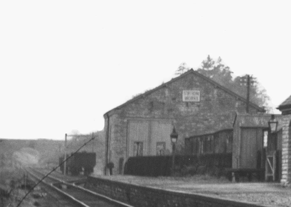 Close up of Binton station's goods shed with doors closed and with wagons standing on the siding beneath the loading gauge