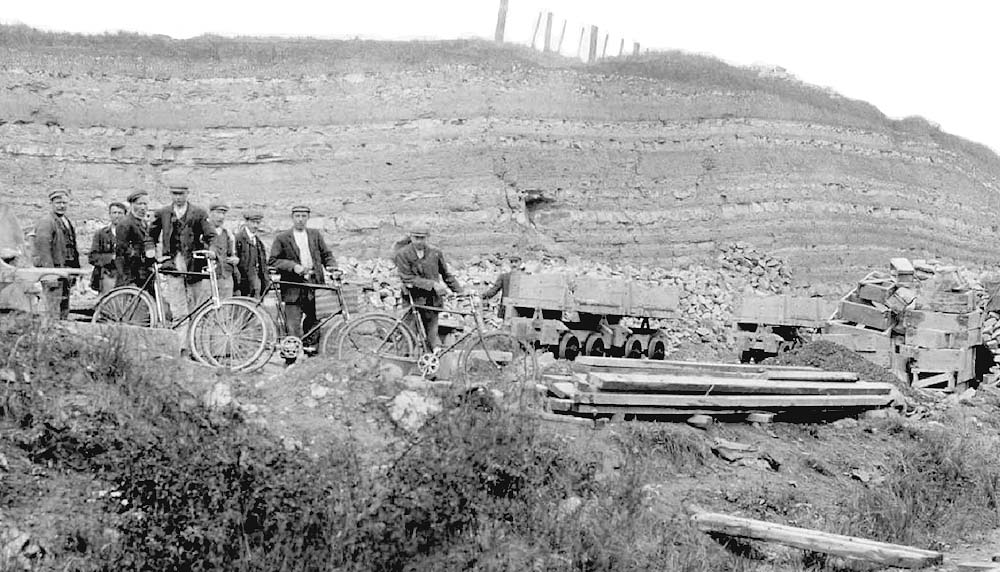 Close up showing some of the narrow gauge side tipping wagons on the right as some of the workmen prepare to cycle home
